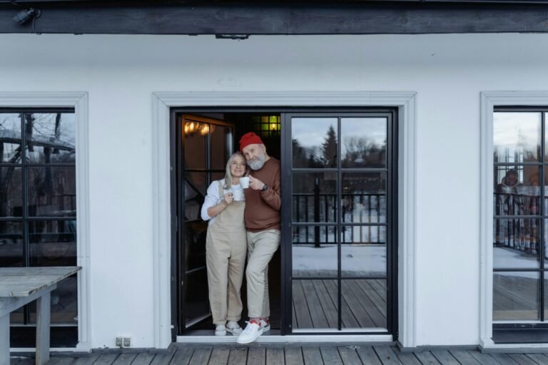 Happy senior couple enjoying coffee on their porch in winter.