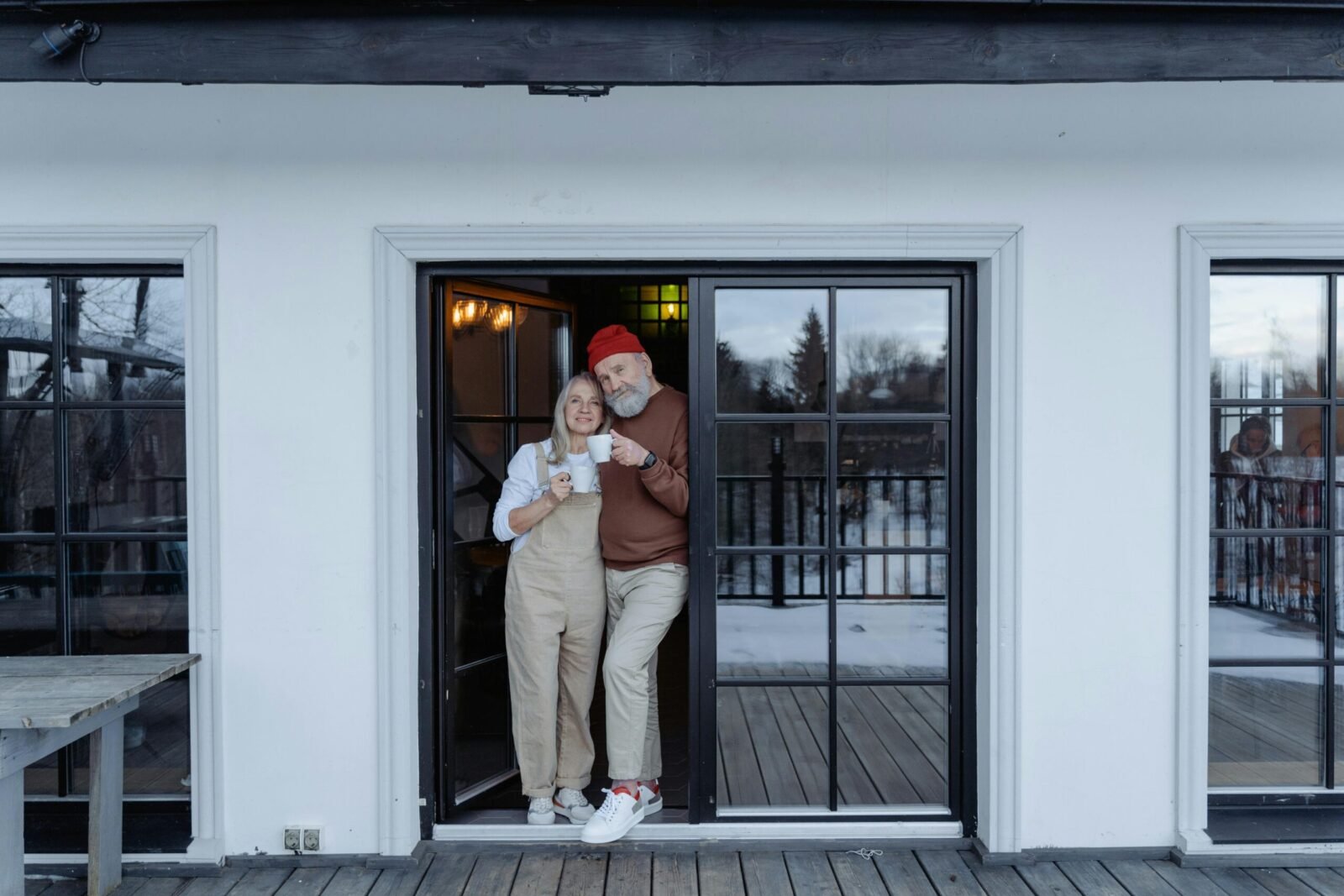 Happy senior couple enjoying coffee on their porch in winter.